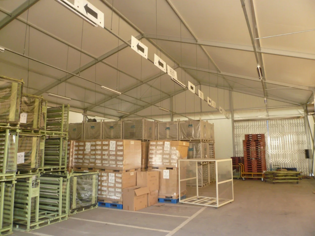 Aluminum clear span storage structure utilized as a logistics warehouse with high vertical clearance for inventory stacking.