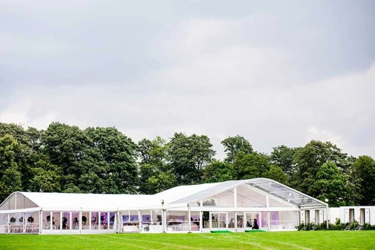 Luxury curved roof marquee structure featuring panoramic glass panels for premium garden events.