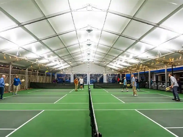 Aerial view of an arch roof clear span tent covering outdoor padel courts at a sports facility.