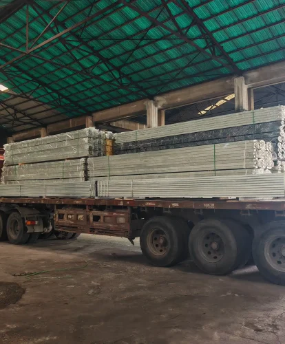 Flatbed truck loaded with wrapped aluminum profiles for clear span tents inside a factory.