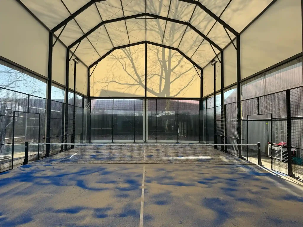 Indoor padel court protected by a clear span tent structure with a translucent canopy.