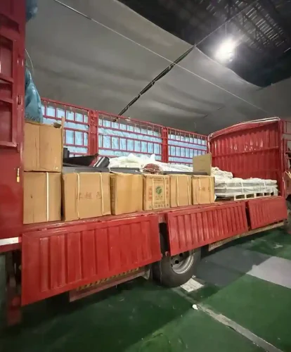 Red truck loaded with cardboard boxes and packaged tent accessories inside a warehouse.
