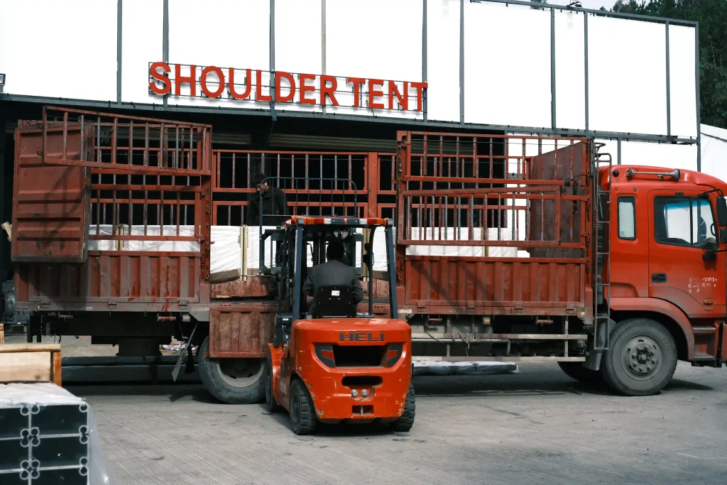 Forklift loading packaged aluminum tent structures onto a truck at the Shoulder Tent factory.