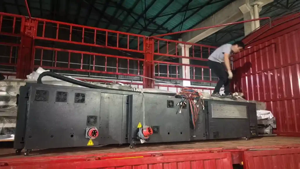 Heavy duty industrial electrical control unit with red and yellow connectors being loaded onto a red shipping truck.