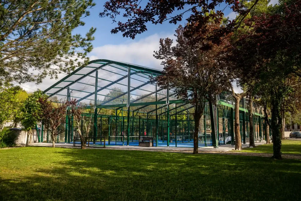 Well-lit interior of a clear span pickleball tent at night, featuring active players on courts.