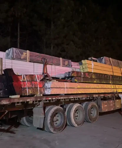 Heavy truck loaded with clear span tent structural beams and parts ready for night transport.