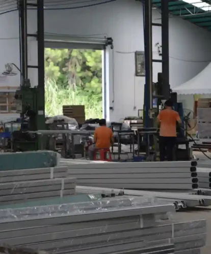 Workers processing aluminum tent components inside a spacious manufacturing facility.