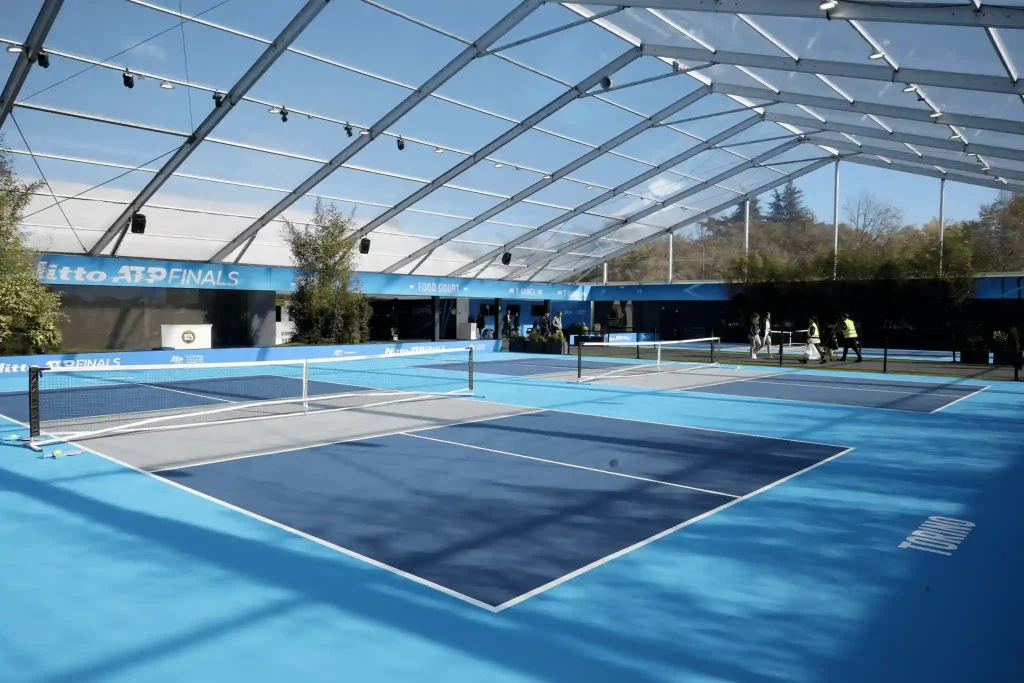 Professional blue sports courts covered by a clear span tent with a fully transparent roof.