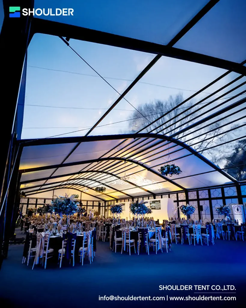 Interior of an arcum clear span tent with black aluminum roof beams setup for a wedding.
