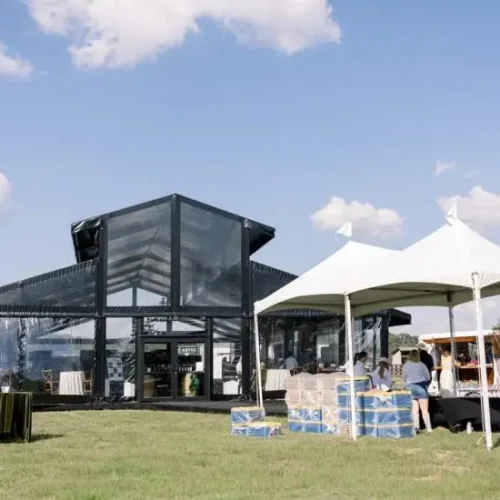 Exterior of a black aluminum clear span tent featuring an elevated ridge and glass walls.