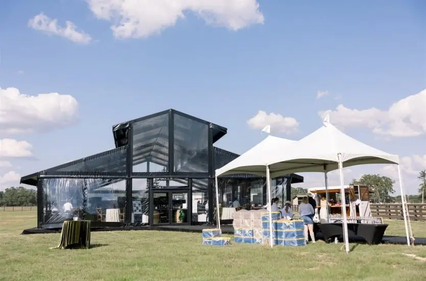 Exterior of a black aluminum clear span tent featuring an elevated ridge and glass walls.