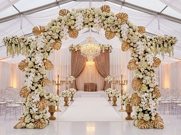 Clear roof wedding marquee interior with white silk lining, floral arches, and seating.