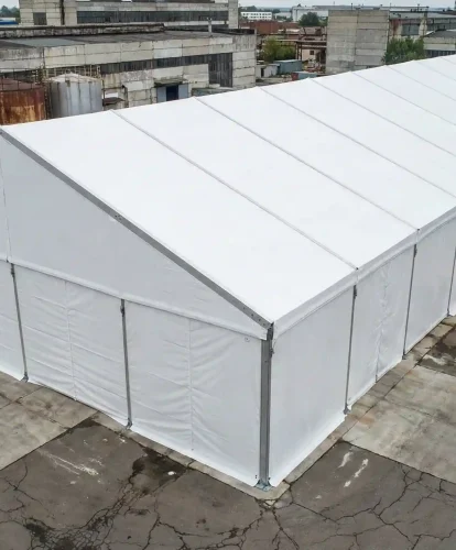 High angle view of an extra long white clear span storage tent in an industrial facility.