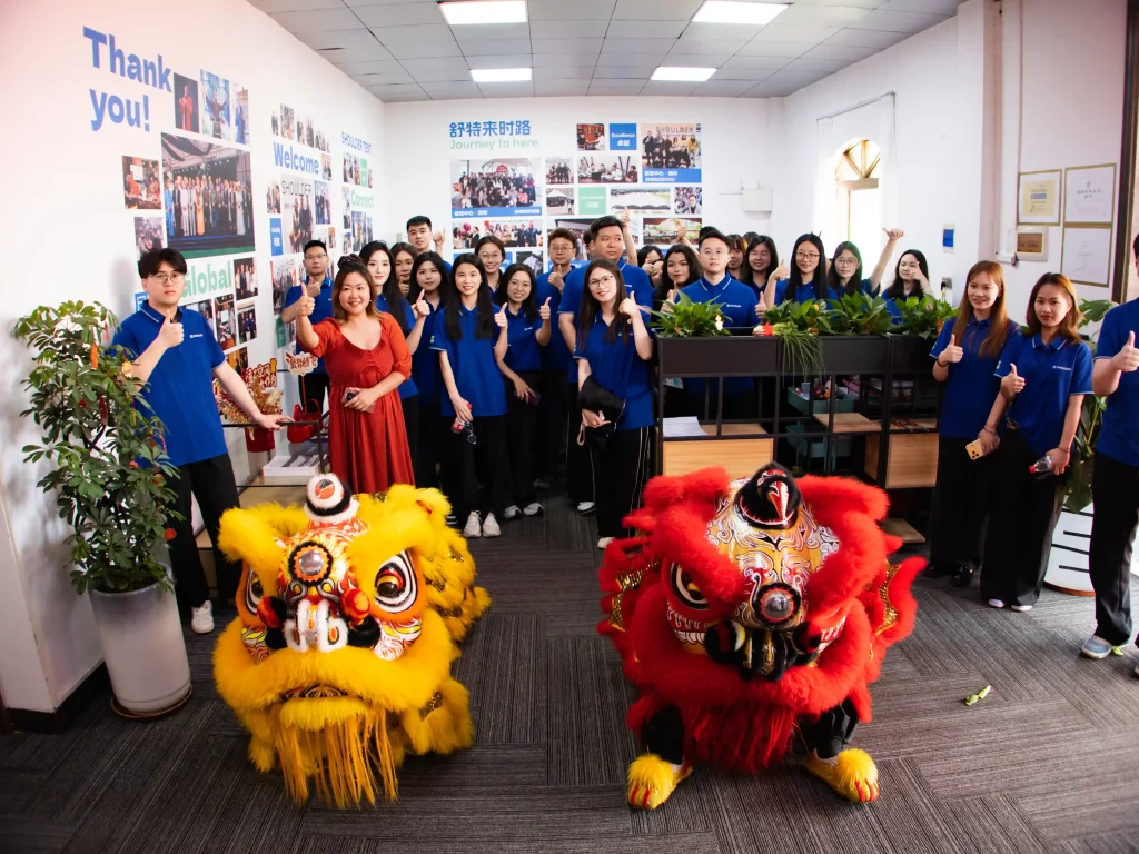 Office team posing with lion dance costumes inside the new Shoulder Tent headquarters.