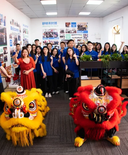 Office team posing with lion dance costumes inside the new Shoulder Tent headquarters.