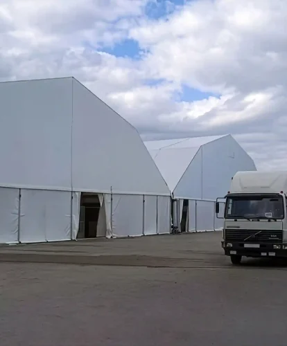 White clear span warehouse tents installed in an industrial yard with a truck parked outside.
