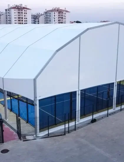 Large white polygonal roof clear span tent covering multiple outdoor sports courts.