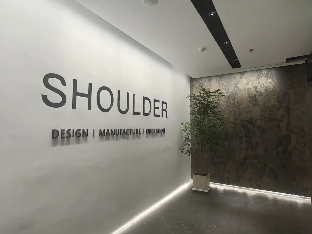 Orange display wall with 3D Shoulder logo next to a small aluminum tent frame sample.