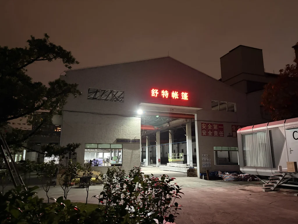 Night view of the Shoulder Tent aluminum workshop facility showing manufacturing capacity.