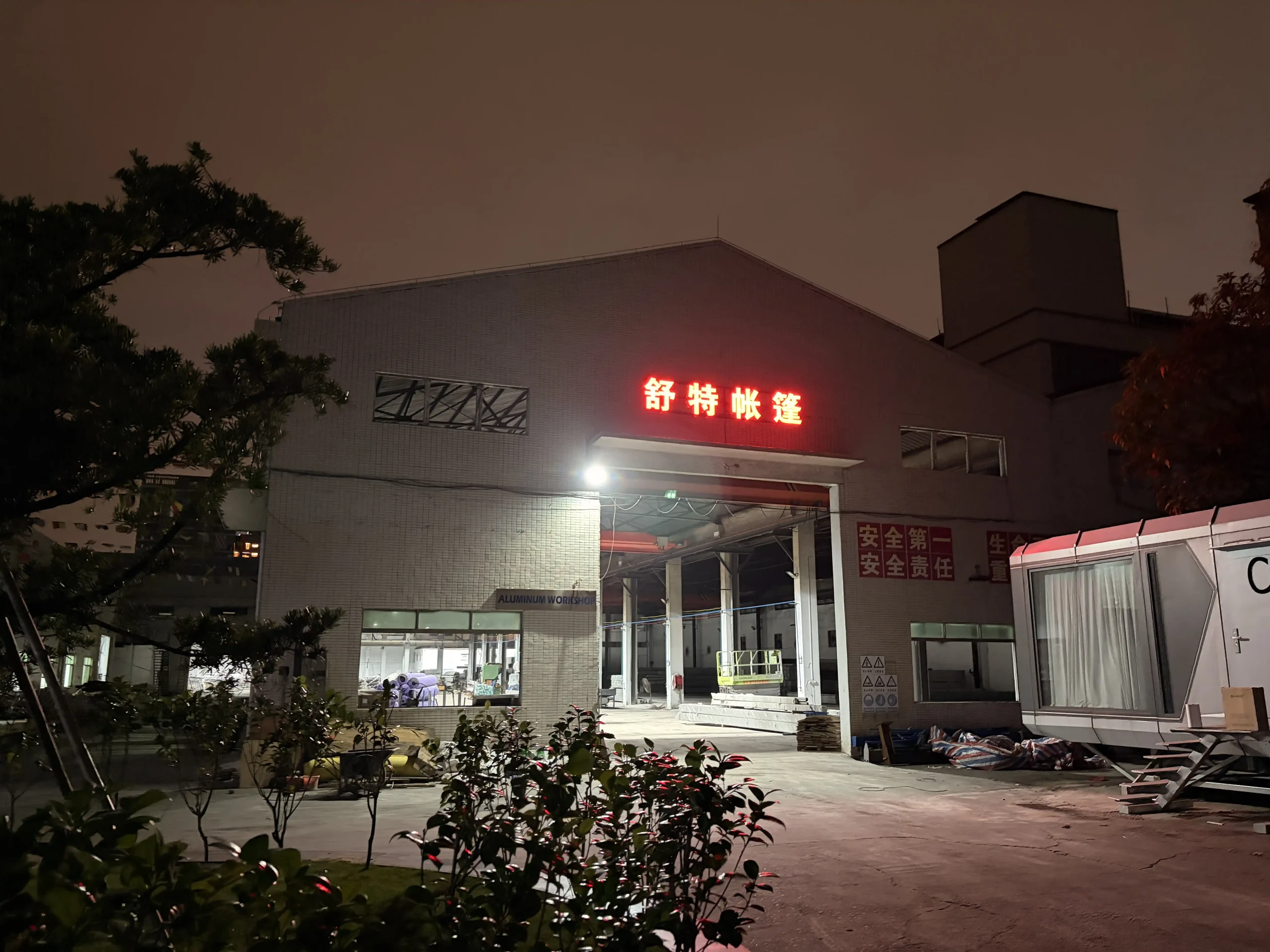 Night view of the Shoulder Tent aluminum workshop facility showing manufacturing capacity.
