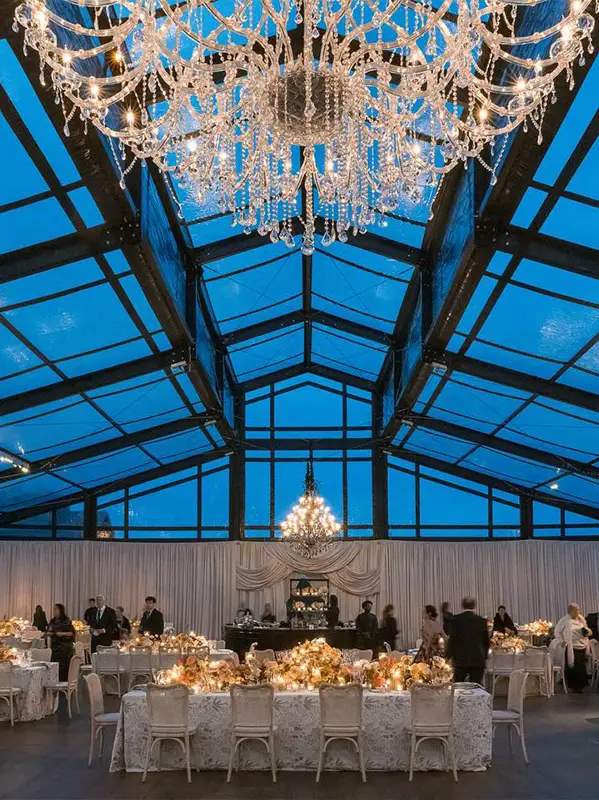 Night view of a luxury clear roof marquee with black aluminum frame and crystal chandeliers.