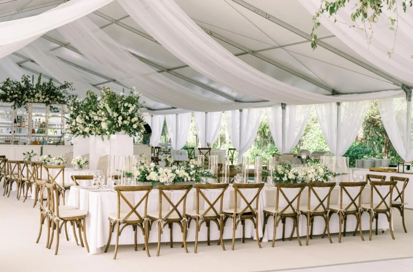 Clear span marquee interior showing transparent roof sections, white drapes and long tables.