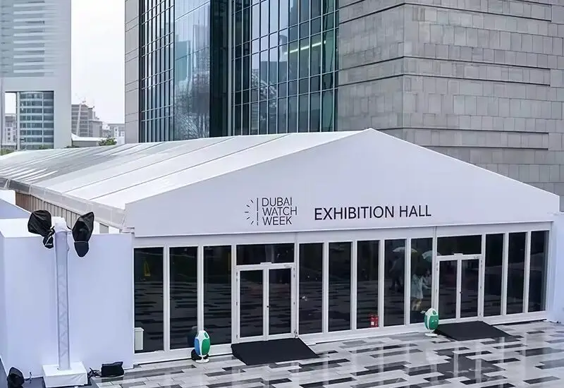 White clear span exhibition tent with glass entrance doors set up in a modern urban plaza.
