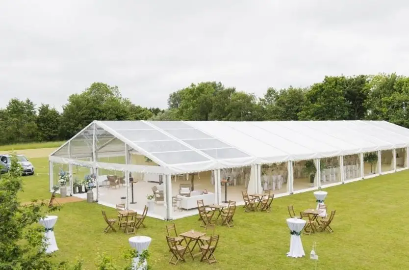 Outdoor clear span event tent with transparent roof panels and walls set up for a banquet.