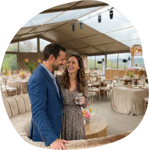 Happy couple standing inside an elegantly furnished clear top aluminum event tent.
