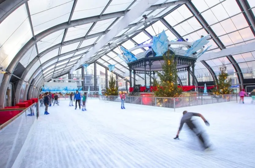 Transparent curved roof aluminum structure housing a winter indoor ice skating rink.