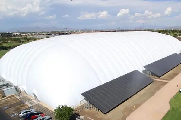 Aerial view of a massive white air dome with solar panels on its side structures.