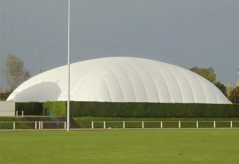 White air-supported structure located next to a green outdoor sports field.