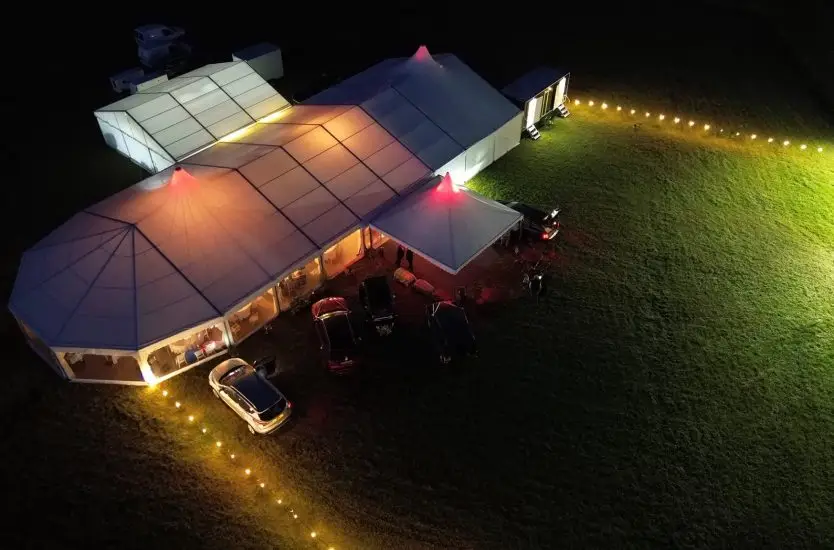 Standard A-frame aluminum event tent on a grassy field with a paved path.