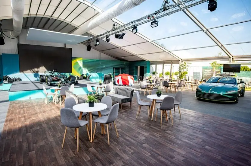 High-end curved roof clear span tent hosting an automotive event with race cars and a stage.