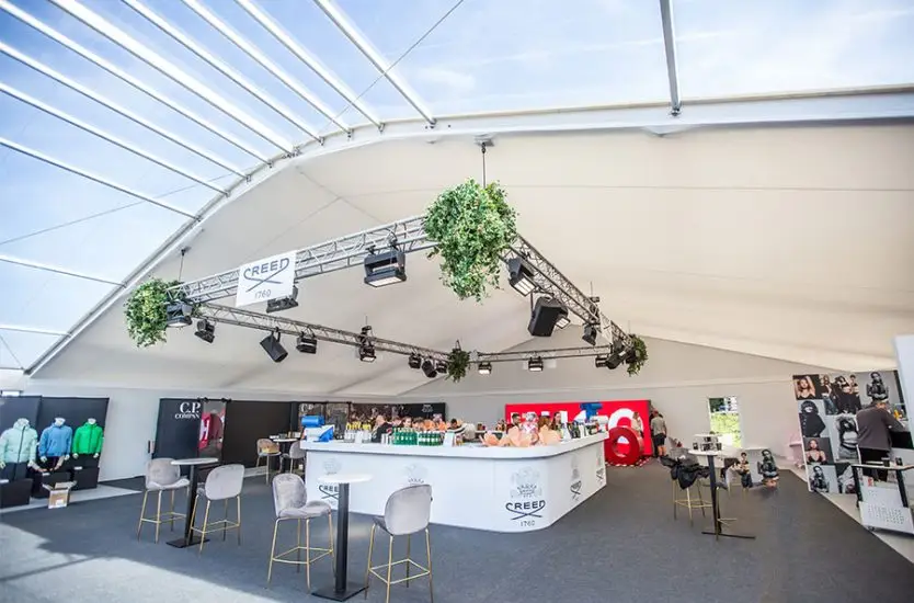 Interior of an aluminum curved roof tent set up for a brand activation event with a custom bar.