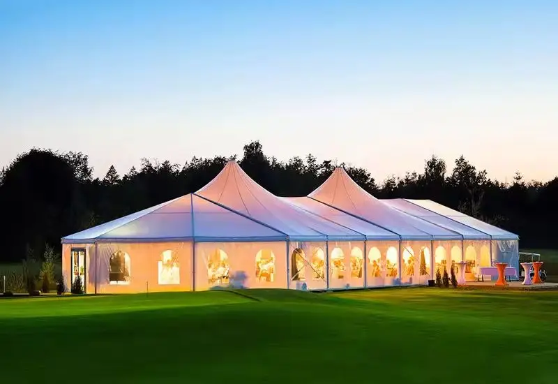 A very long A-frame aluminum exhibition tent with a multi-peak roof on grass.