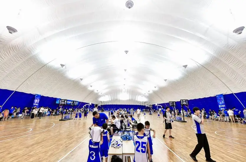 Inside a large inflatable sports dome with a wooden floor used for basketball games.