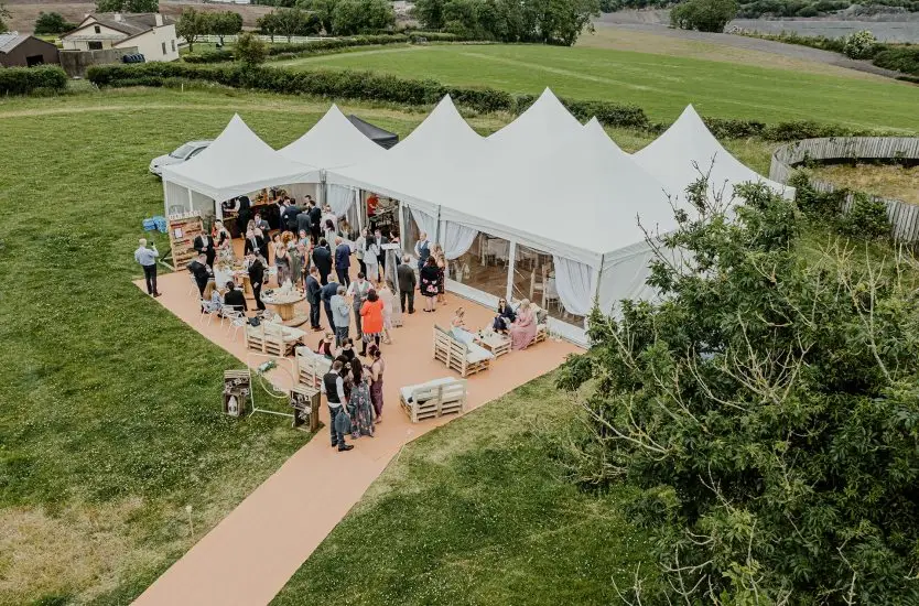 Aerial view of a large modular multi-peak event tent with wooden flooring and guests.