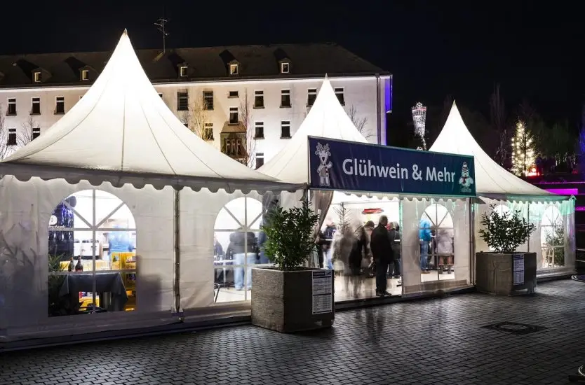 Connected white vendor tents with clear PVC windows at a night outdoor market.