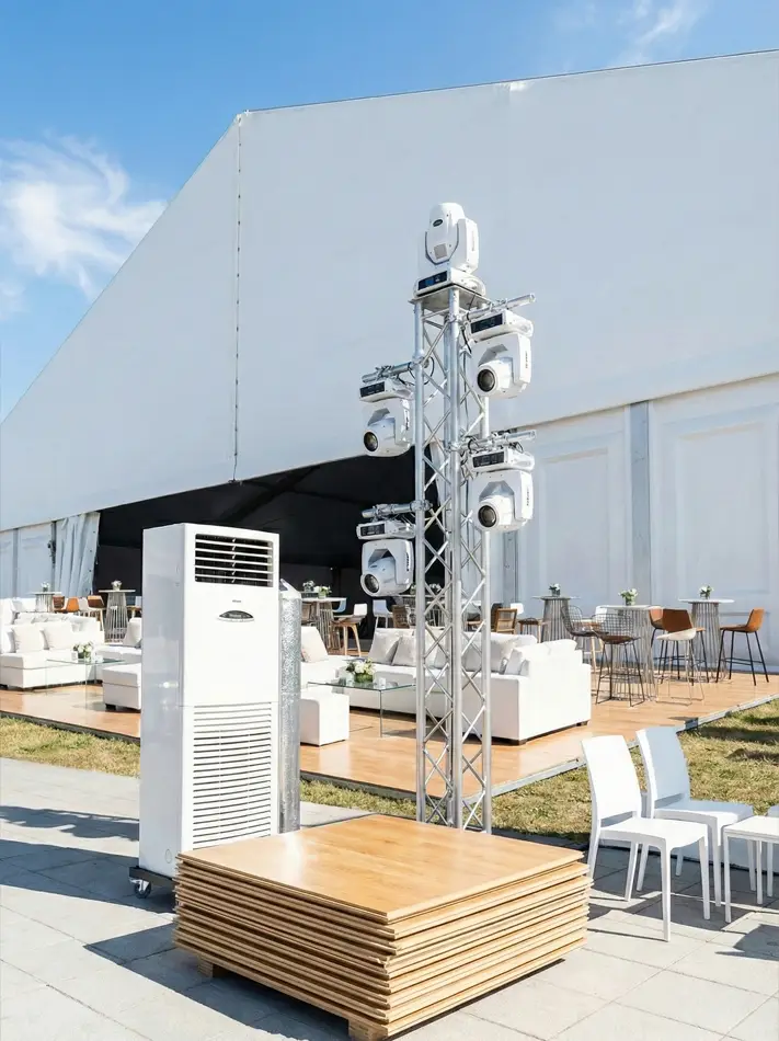 Event setup showing a portable air conditioner, lighting truss, and flooring next to a tent.