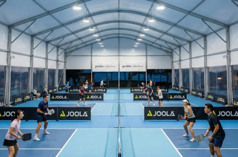 Players competing on indoor pickleball courts housed within a modular sports tent.