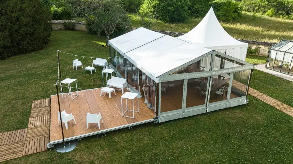 Aluminum frame event tent with clear PVC sidewalls and wooden flooring system.
