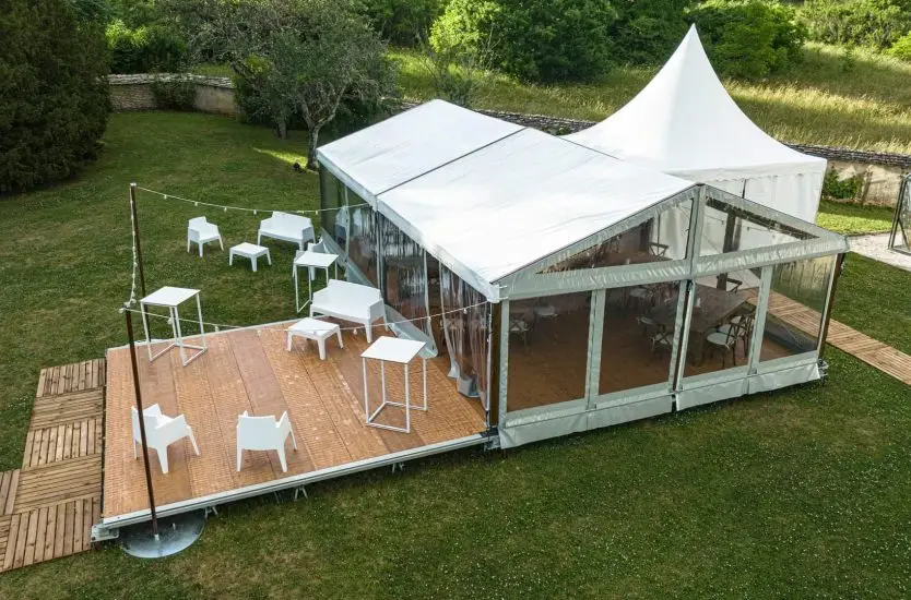 Aluminum frame event tent with clear PVC sidewalls and wooden flooring system.