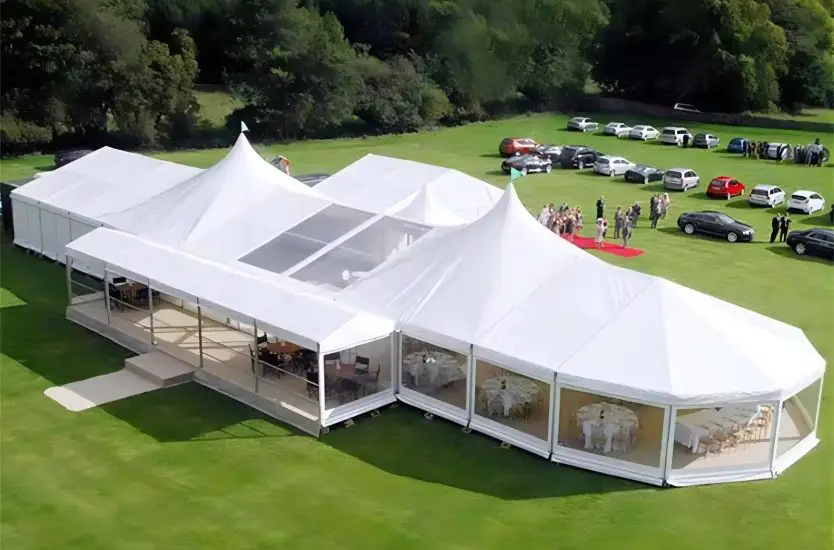 Large white polygonal aluminum clear span structure housing an indoor pool near water.