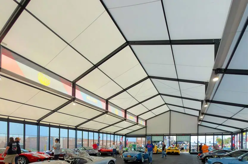 Interior of a black aluminum clear span tent with glass walls hosting a classic car exhibition.